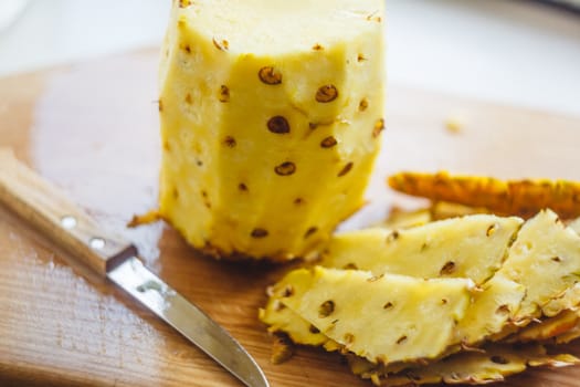 Pineapple cleaning, chunks, knife lie on the board.