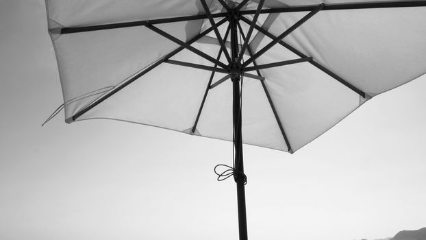 White fabric color texture beach umbrella and brown wood tripod with white cloud and clear blue sky summer sunlight day in low angle view camera for travel asia Thailand Pattaya.