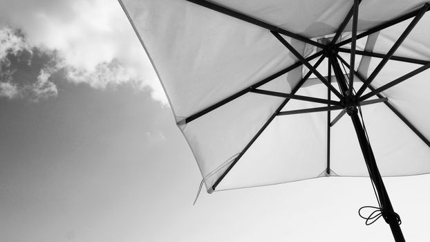 White fabric color texture beach umbrella and brown wood tripod with white cloud and clear blue sky summer sunlight day in low angle view camera for travel asia Thailand Pattaya.