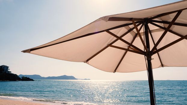 White fabric color texture beach umbrella and brown wood tripod with white cloud and clear blue sky summer sunlight day in low angle view camera for travel asia Thailand Pattaya.