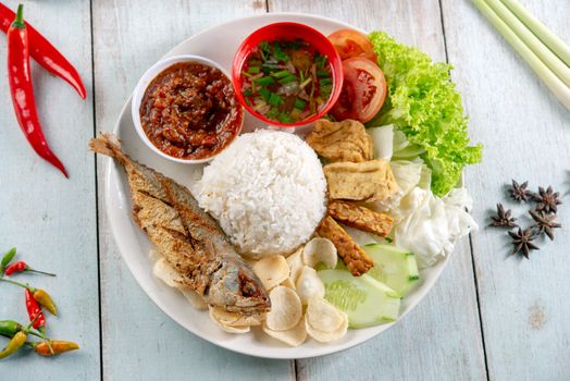 Fried mackerel fish rice with sambal, popular traditional Malay or Indonesian local food. Flat lay top down overhead view.
