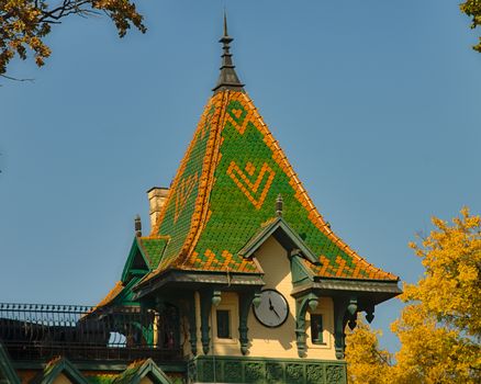 Top of tower like building with clock and green and orange square roof