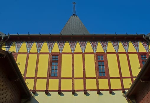 View on old style yellow wall with two windows and square tower on a building