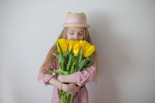 Pretty teen girl smelling yellow tulips, focus on flowers