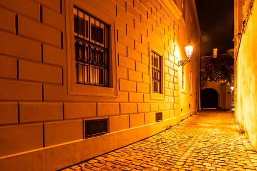 Narrow cobbled street illuminated by street lamps of Old Town, Prague, Czech Republic.