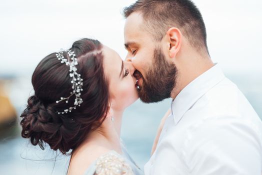 same couple with a bride in a blue dress walk along the ocean shore