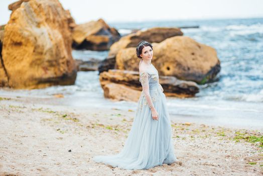 bride in a blue light dress walking along the ocean