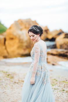 bride in a blue light dress walking along the ocean