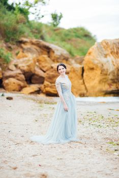 bride in a blue light dress walking along the ocean