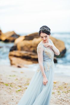 bride in a blue light dress walking along the ocean