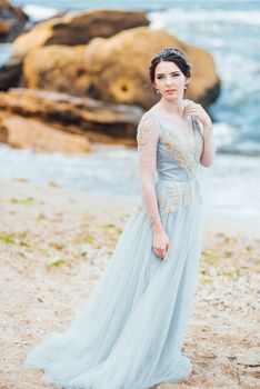 bride in a blue light dress walking along the ocean