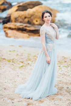 bride in a blue light dress walking along the ocean