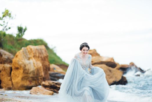 bride in a blue light dress walking along the ocean