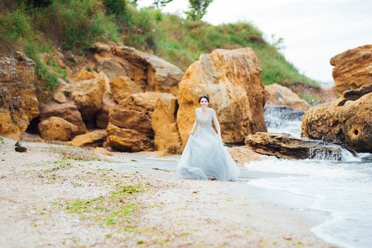 bride in a blue light dress walking along the ocean