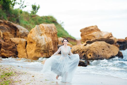 bride in a blue light dress walking along the ocean