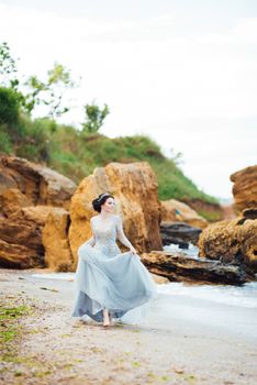 bride in a blue light dress walking along the ocean