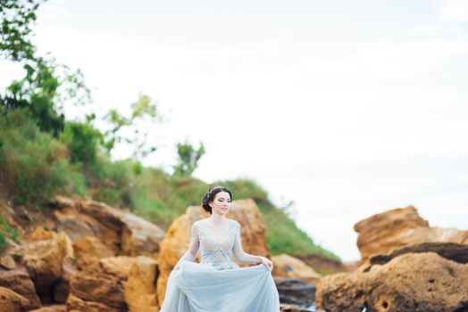 bride in a blue light dress walking along the ocean