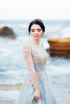 bride in a blue light dress walking along the ocean