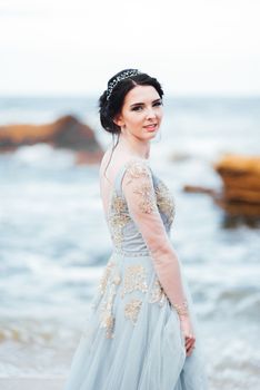 bride in a blue light dress walking along the ocean