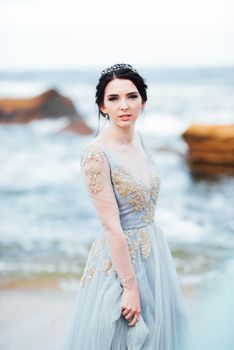 bride in a blue light dress walking along the ocean