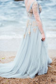 bride in a blue light dress walking along the ocean