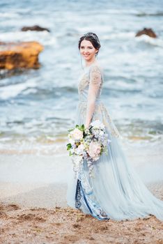 bride with a bouquet of flowers on the beach near the water