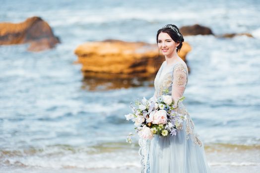 bride with a bouquet of flowers on the beach near the water