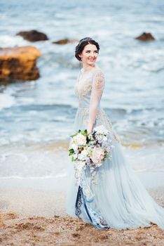 bride with a bouquet of flowers on the beach near the water