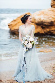 bride with a bouquet of flowers on the beach near the water