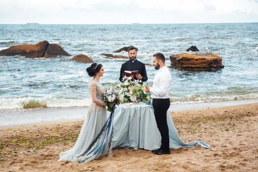 wedding couple on the ocean with a priest