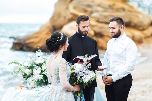 wedding couple on the ocean with a priest