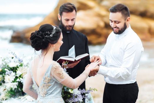 wedding couple on the ocean with a priest