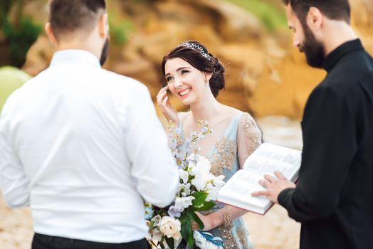 wedding couple on the ocean with a priest