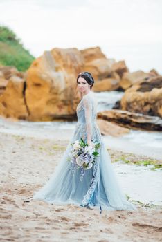 bride with a bouquet of flowers on the beach near the water
