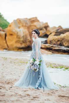 bride with a bouquet of flowers on the beach near the water