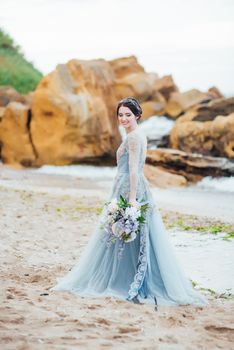 bride with a bouquet of flowers on the beach near the water