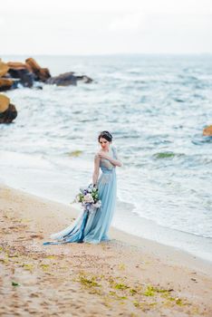 bride with a bouquet of flowers on the beach near the water