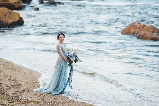 bride with a bouquet of flowers on the beach near the water