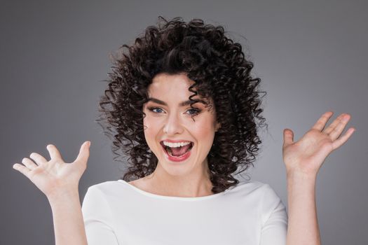 Surprised young woman shouting over gray background. Looking at camera