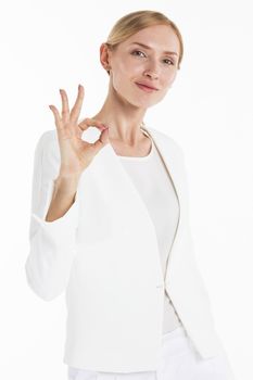 Beautiful mid adult businesswoman showing okay hand sign gesture isolated on white background