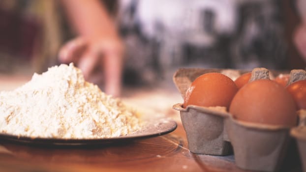 Ingredients for baking homemade bread. Eggs, flour. Wooden background, side view. Soft focus and light