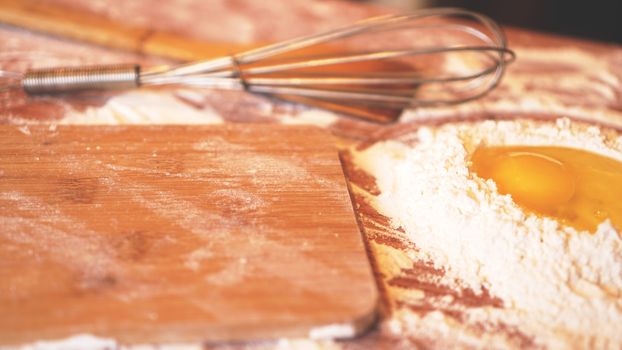 Ingredients for baking homemade bread. Eggs, flour. Wooden background, side view. Soft focus and light
