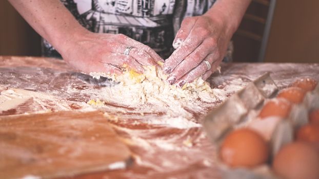 Cooking and home concept - close up of female hands kneading dough at home. Soft focus