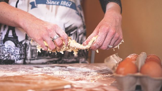 Cooking and home concept - close up of female hands kneading dough at home. Soft focus