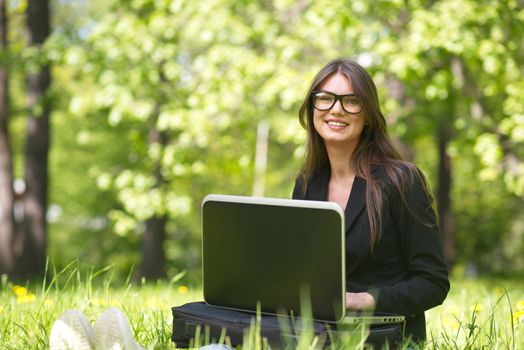 Beautiful business woman in suit using laptop computer in the park