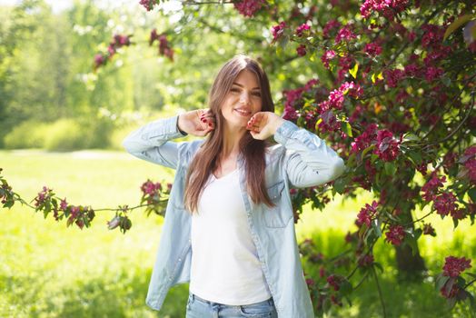 Beautiful young brunette woman standing near blooming tree