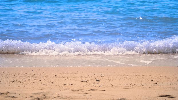 Clear light blue color sea water or liquid marine waving and splashing to light brown color sand beach on summer day in Pattaya Thailand and no people swimming because of hot weather.