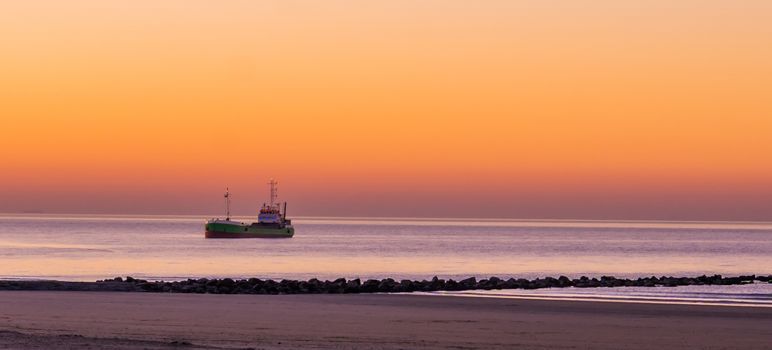 lighted ship sailing in the sea at sunset, the Belgian coast, nature and transport background