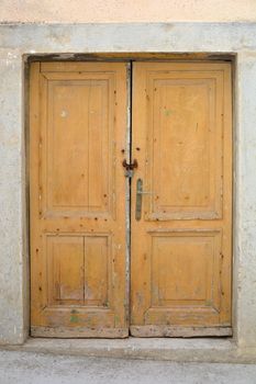 Old wooden yellow closed and locked door 