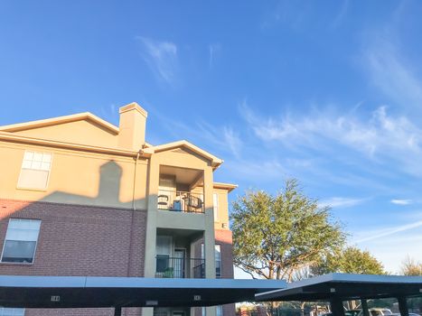 Typical apartment building complex in Lewisville, Texas, USA. Low angle view of multi-stories rental real estate with covered parking at sunset with cloud sky